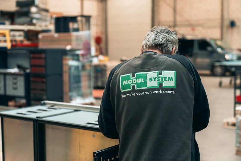 Modul-System employee wearing a Modul-System jacket in a bright industrial workshop.